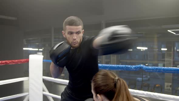 Young Woman Boxing with Coach in Gym