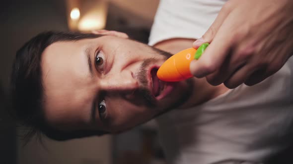 Man Bites Off a Children's Plastic Toy Carrot and Looks Into the Camera