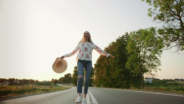 Beautiful Young Female with Nice Hat Smiling and Running on Asphalt Road alt