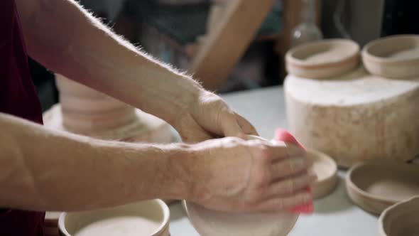Man Hands Makes Clay Plates in Pottery Workshop Top Close Up View Focus on Stained Hand alt