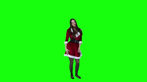 Attractive female dancer in a Christmas costume spinning and dancing in front of a green screen alt