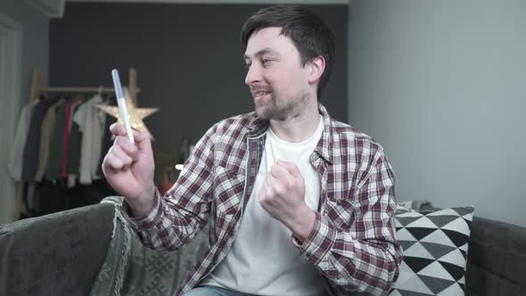 Young Caucasian Man Holding Pregnancy Test in His Hands Very Excited and Happy with Result and alt