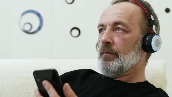 Modern Middleaged Man Listens to Music in Wireless Headphones alt