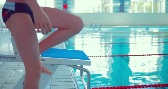 Closeup of an Adolescent Athlete on the Starting Block Before Jumping Into the Pool alt