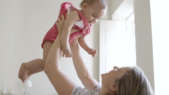 Caucasian Mother Lifting Cute Daughter Over Head alt