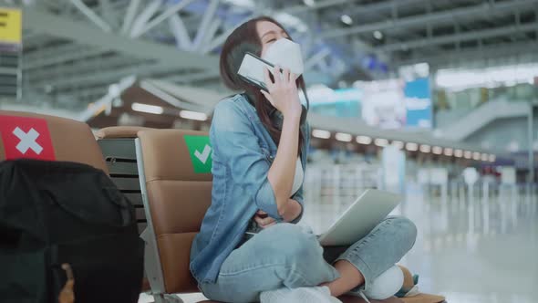 young asian adult traveller wearing face mask hand hold smartphone alt