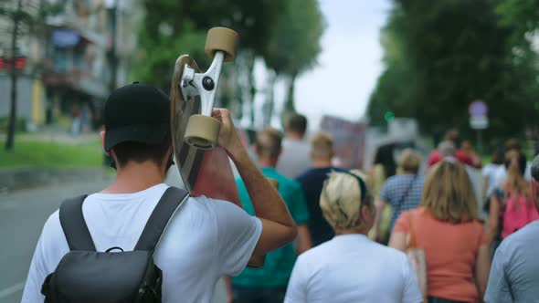 Political Activist Skater with Longboard in Opposition Strike Crowd Marching