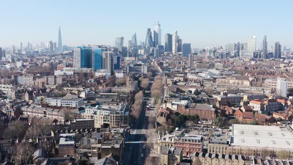 Dolly back drone shot of city of London skyscraper cluster over Whitechapel road alt