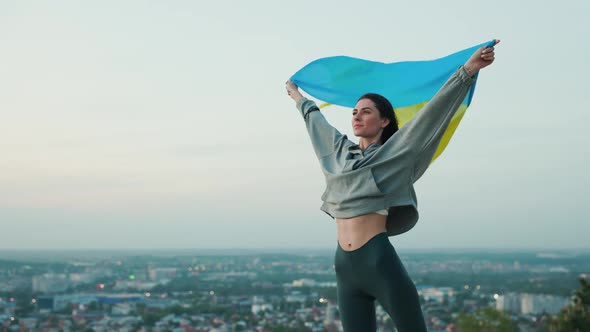 Portrait of Beautiful Ukrainian Woman with Flag Unfurling in the Wind in Hands