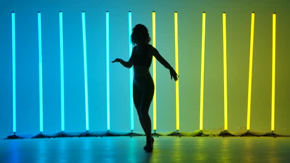 A Slender Woman in Leggings and a Top Is Practicing Salsa Movements in Slow Motion alt