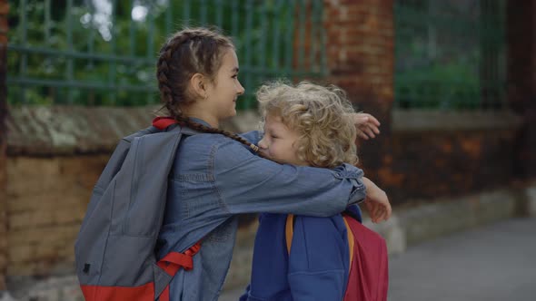 The Schoolgirl Hugs Her Little Brother and Smilling on the Street alt