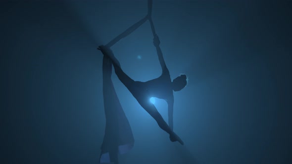 Silhouette of Graceful Aerial Gymnast Performing Acrobatic Stunts and Stretching on Aerial Silk alt