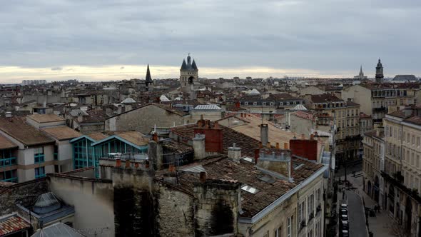 French city of Bordeaux rooftops with Cailhau City Gate and pigeons flying, Aerial pedestal lowering alt