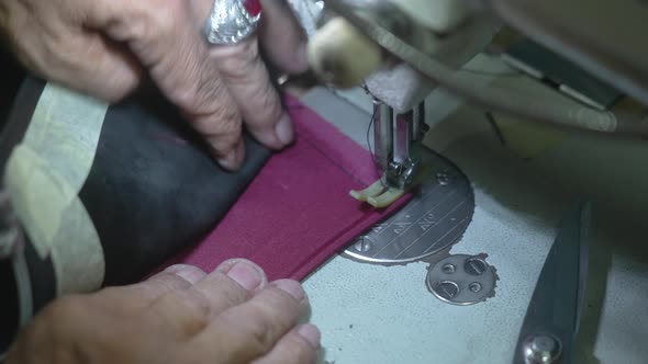 Closeup of Old Hands of Anonymous Tailor Who is Sewing a Brown Lining to Leather Jacket on Sewing alt