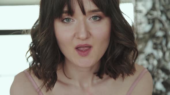 Happy Brunette Smiling and Blowing Golden Wrappers on Camera alt