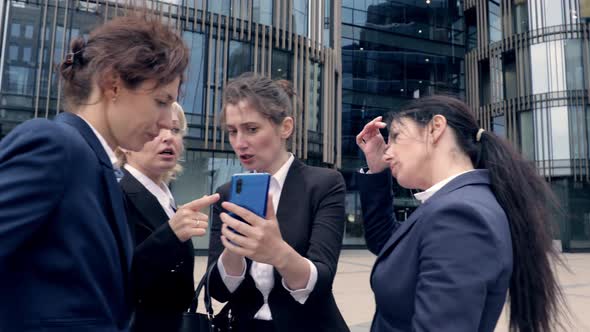 Group of Female Colleagues Seriously Discuss What They See in a Smartphone