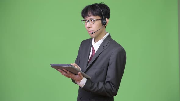 Young Asian Businessman Using Digital Tablet While Working As Call Center Representative alt
