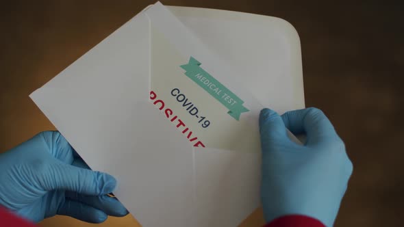 Person Opening Envelope with Certificate with Positive Results in Covid-19 alt