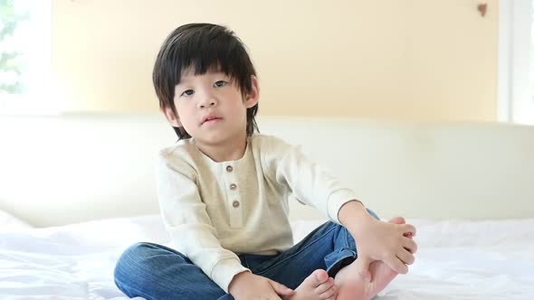 Cute Asian Child Sitting On Bed alt