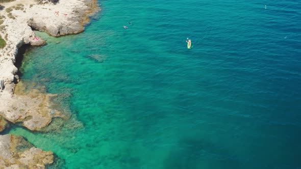 Sportsmen Sail Green Row Boat Along Sea Water Past Cliffs alt