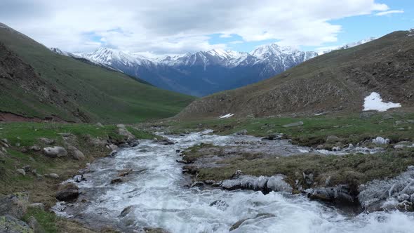 Water Stream on the Background of Snow-capped Mountains