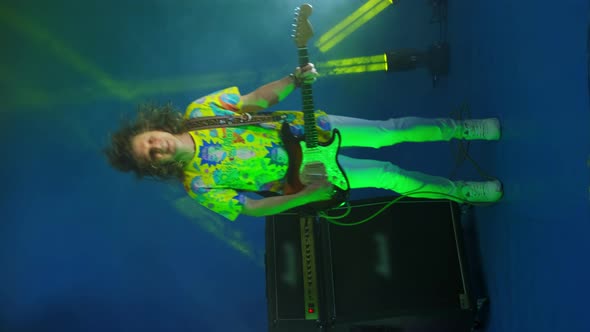 Vertical Video of a Crazy Jumping Rock Guitarist with a Guitar in His Hands on a Colored Neon alt