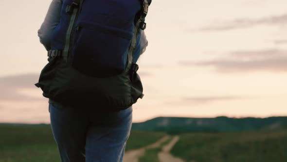 Active Healthy Caucasian Woman with Backpack is Walking Towards a Distant Mountain alt