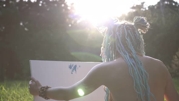 Young Attractive Woman Artist Paints a Picture on a Sunset Background alt