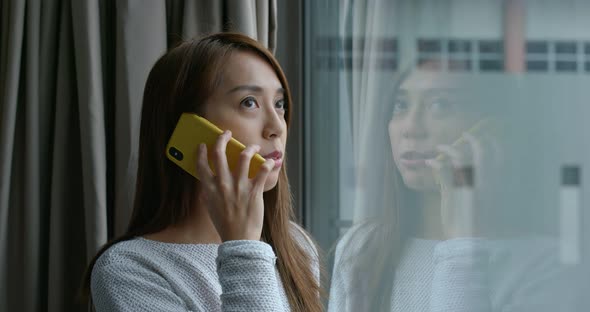 Woman chat on cellphone and stand beside the window