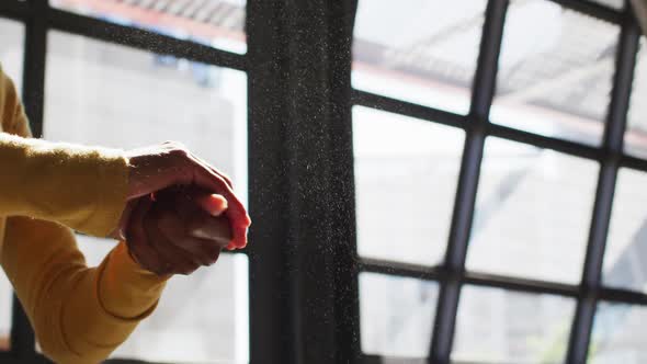 Mixed race male cafe worker wearing face mask disinfecting hands of female coworker alt