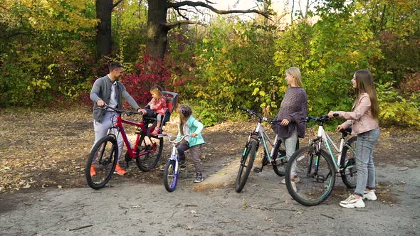 Family Standing with Bicycles in Park After Cycle Ride alt