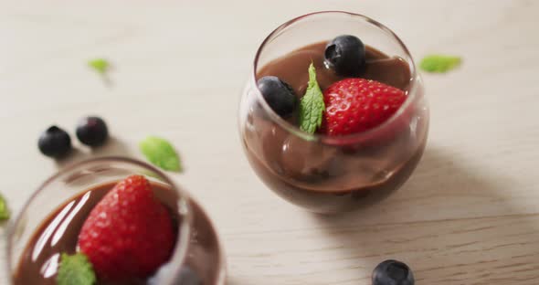 Video of chocolate pudding with strawberries and bluberries on a wooden surface alt
