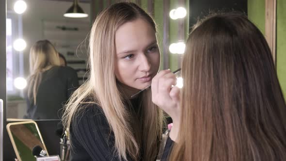 Attractive Caucasian Make Up Artist Doing Makeup for Asian Girl in Beauty Salon alt