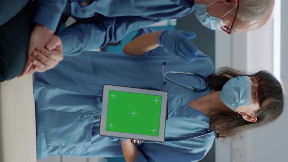 Vertical Video Nurse and Retired Man Looking at Green Screen on Digital Tablet alt
