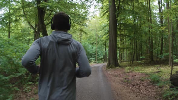 Man Running Through Forest Wearing Headphones