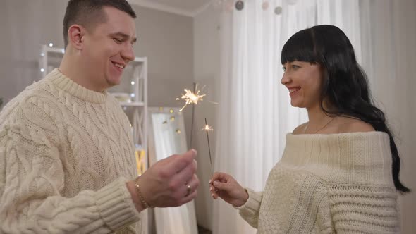 Smiling Happy Young Husband and Wife Holding Sparklers and Talking in Slow Motion on New Year's Day alt