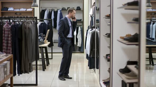 A Side View General Shot of a Dark Haired Business Man Choosing a New Clothing Style for Himself and