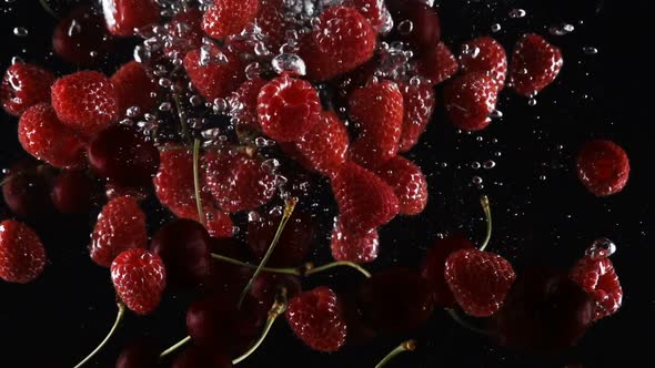 Mix of Ripe Berries Falls Into the Water on a Black Background