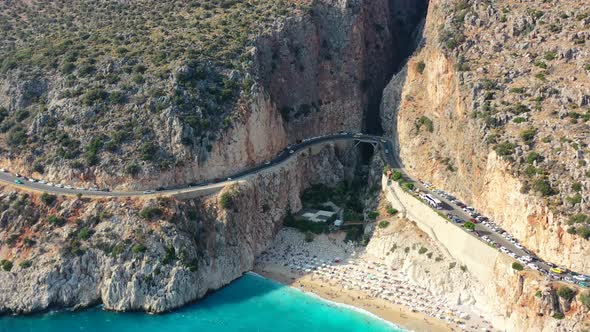 aerial drone panning left during a sunset afternoon at Kaputas Beach in Kas Turkey as cars drive alo alt