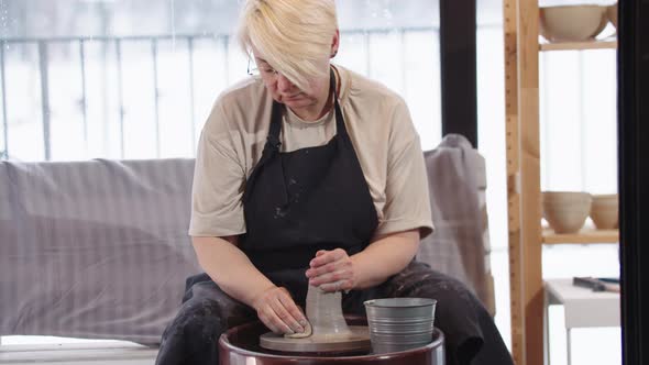 An Elderly Woman Softening the Piece of Clay in the Workshop alt