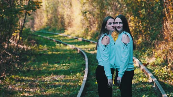 Smiling Young Twins Women Standing Together on Railroad alt