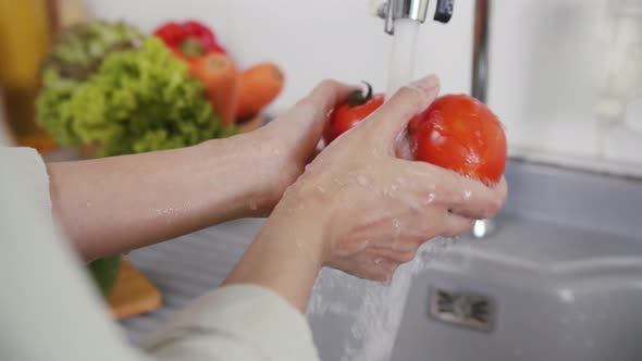 Close up of Woman Hand Washing a Fresh Red Organic Tomato