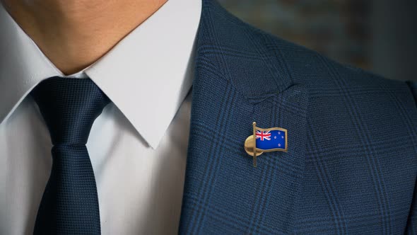 Businessman Walking Towards Camera With Country Flag Pin New Zealand alt