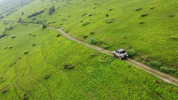 Black Suv Rides On A Mountainous Terrain On A Dirt Road.  Aerial View. 