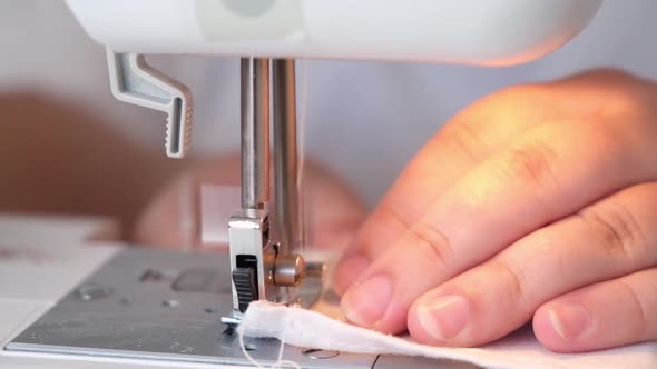 A Woman is Sewing the Hem of Curtains the Edge of a Pillowcase Clothes Sheets on Sewing Machine
