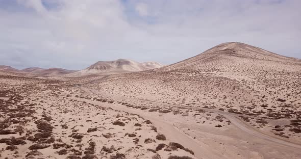 Path road in the middle of a mountains sand desert with blue bright sky in background. Arid climate