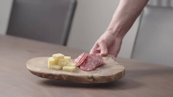 Slow Motion Man Put Olive Board with Vintage Cheese and Salae on Walnut Table