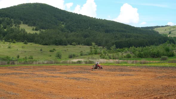 Farmer Seeding Field with Tractor in Green Countryside of Balkans