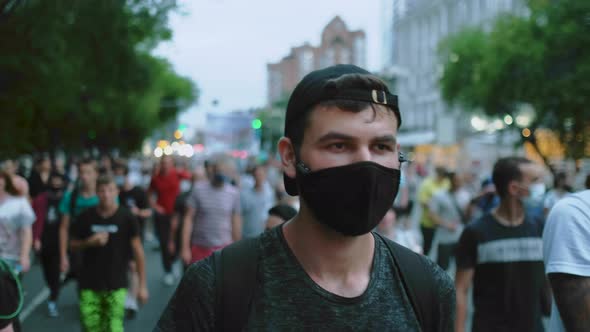 Portrait of Male Rebel Activist in Face Mask Marching in Protesting Riot Crowd