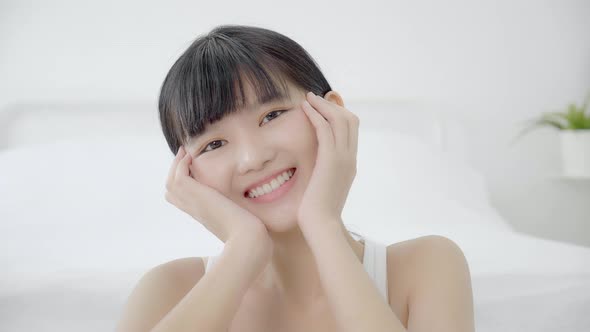 Beautiful young asian woman makeup of cosmetic, girl hand touch cheek on face and smiling.
